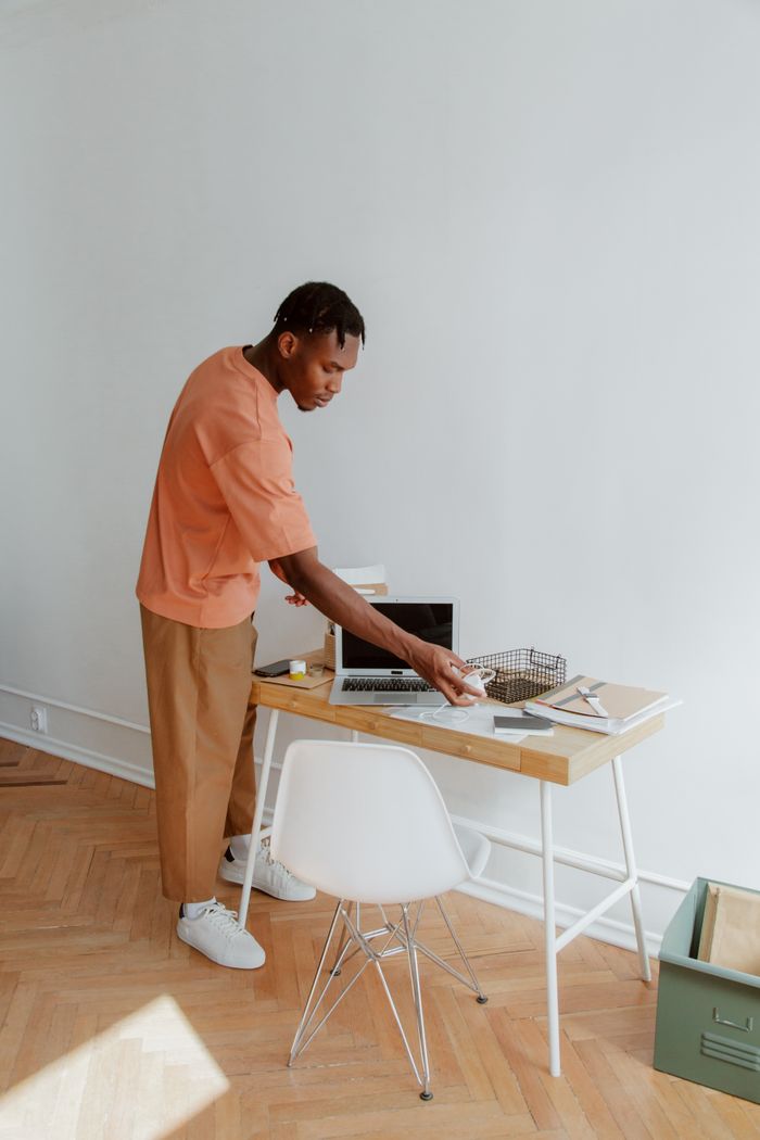 ours-journey A man standing at a desk organizing papers and electronic devices in a modern office setting.